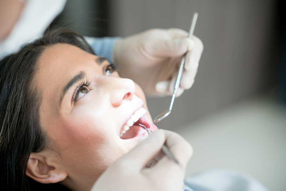 Kvinna som blir undersökt av en tandhygienist